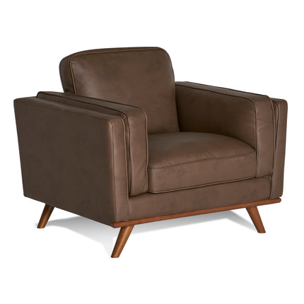 The Maddox Chair, with a mid-century modern design, features plush cushions, clean lines, padded armrests, and angled wooden legs in brown leather, set against a plain white background.