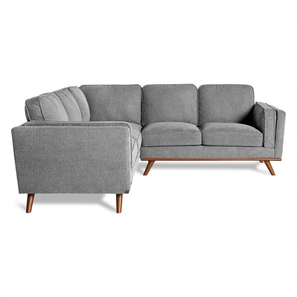 The Maddox sectional is a gray, modern sofa featuring three cushioned seats and angled wooden legs. Its minimalist mid-century style stands out against a white background, showcasing the fabric texture and clean lines—ideal for any chic living room.