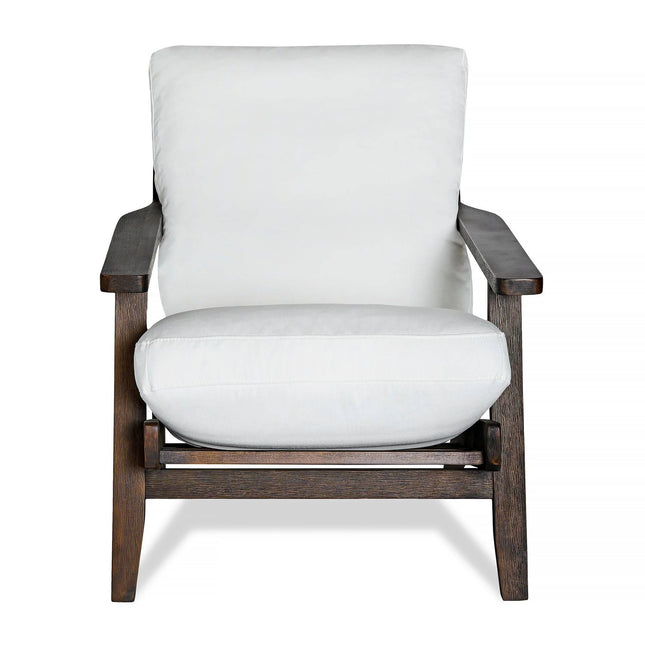 The Peyton Chair features a dark brown wooden frame, thick white cushions for the seat and backrest, and a mid-century style with clean lines and sturdy design for both style and comfort.