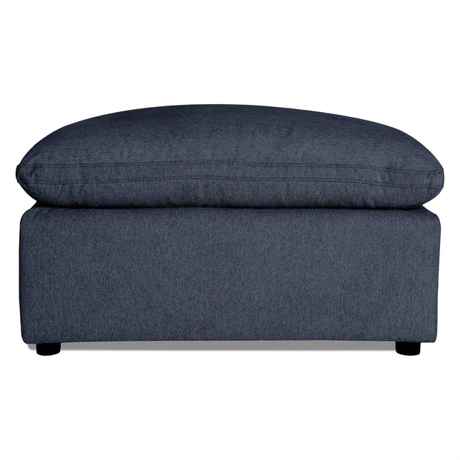 The My Cloud 40 Ottoman features dark gray upholstery with a soft cushioned top and short black legs. Its textured fabric adds to the modern, minimalist design, making it an ideal customizable piece for any living room.
